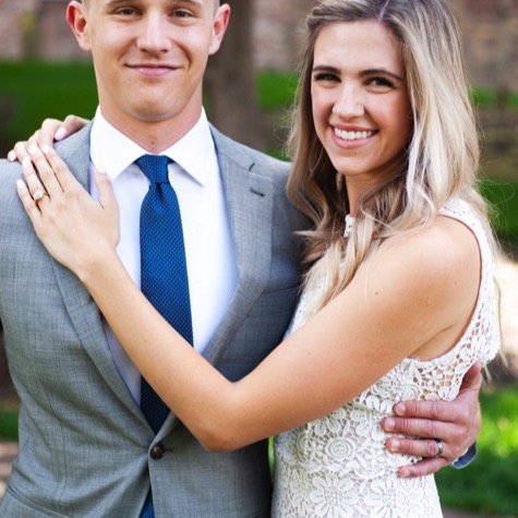 Smiling couple in a gray suit and white lace dress embracing outdoors during a professional couples portrait photography session by Kay Fritze of Fritze Media