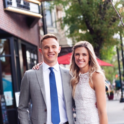 Couple in formal attire smiling together on a downtown city sidewalk during an urban professional couples portrait photography session by Kay Fritze of Fritze Media
