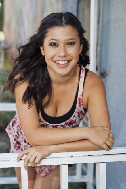 Woman in a floral top smiling while seated outdoors during a professional portrait photography session by Kay Fritze of Fritze Media