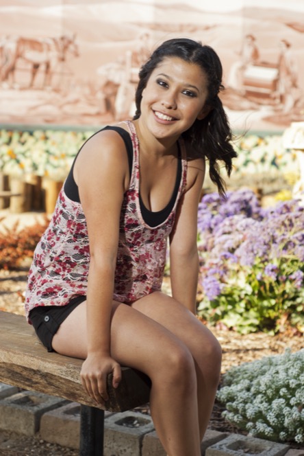 Woman in a floral top posing in a garden setting during a colorful professional portrait photography session by Kay Fritze of Fritze Media