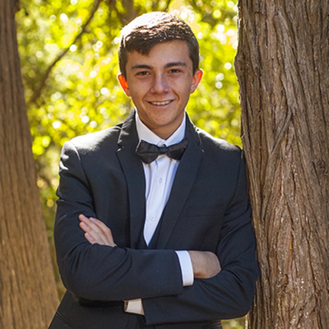 Young man in a formal tuxedo posing with arms crossed outdoors during a professional senior portrait photography session by Kay Fritze of Fritze Media
