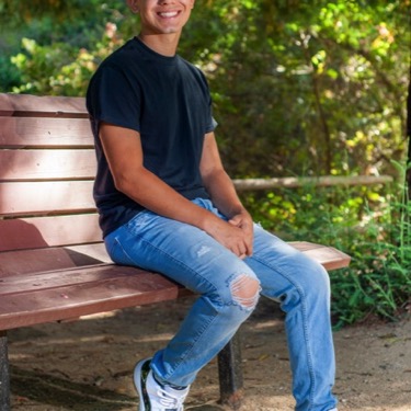 Young man in a blue polo posing in a wooded park during a professional senior portrait photography session by Kay Fritze of Fritze Media