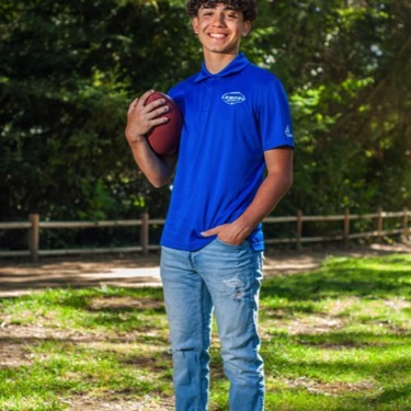 Young man in a blue polo posing in a wooded park during a professional senior portrait photography session by Kay Fritze of Fritze Media