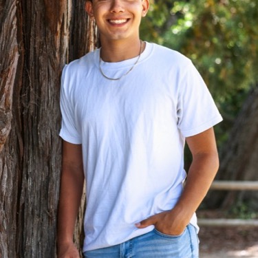 Young man in a white T-shirt posing beside a large tree during an outdoor professional portrait photography session by Kay Fritze of Fritze Media