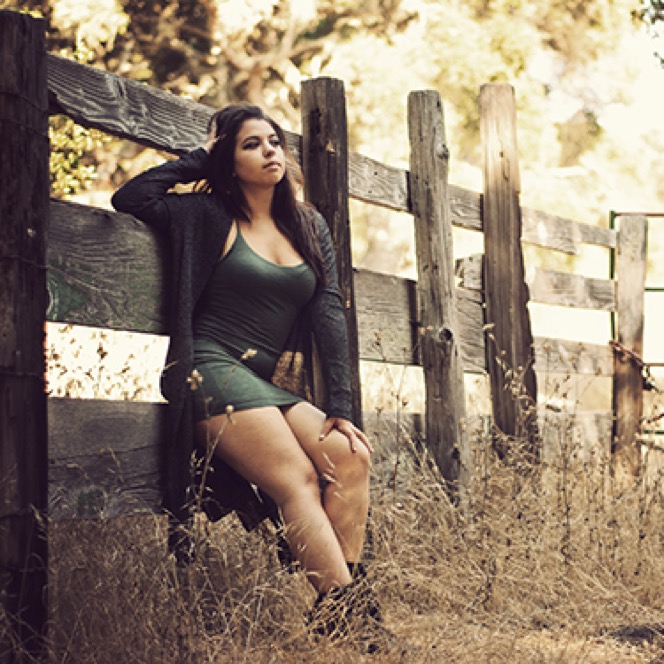 Woman in a black dress posing on a sunlit tree-lined path during an outdoor professional portrait photography session by Kay Fritze of Fritze Media