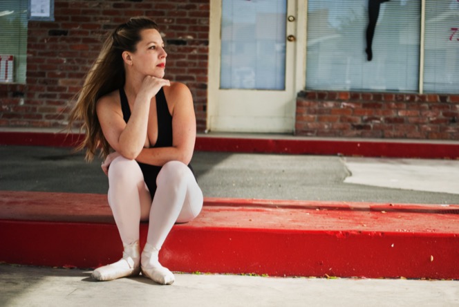 Woman in a black top and light pants seated on red steps outside a building during a professional portrait photography session by Kay Fritze of Fritze Media