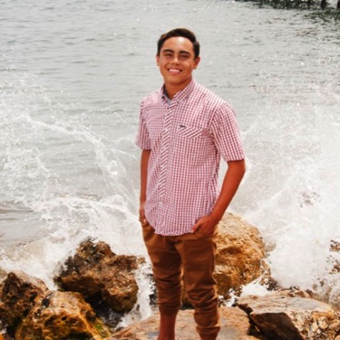 Young man in a pink patterned shirt posing near the water during an outdoor professional portrait photography session by Kay Fritze of Fritze Media