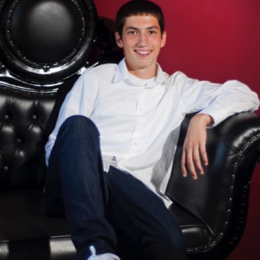 Young man in a white dress shirt seated in a black leather chair during a studio-style professional portrait photography session by Kay Fritze of Fritze Media